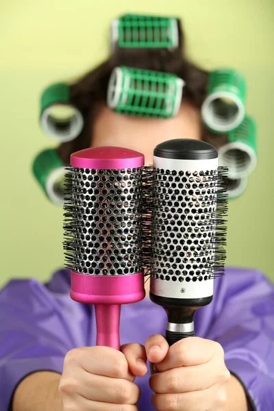 Chica en rulos de pelo sosteniendo peines de pelo sobre fondo colorido — Foto de Stock