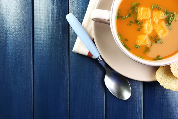 Mrkvová polévka v míse, na barevné dřevěné pozadí — Stock fotografie