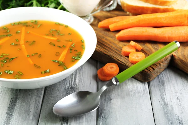 Samenstelling met wortel soep, ingrediënten en kruiden op kleur houten tafel, op lichte achtergrond — Stockfoto