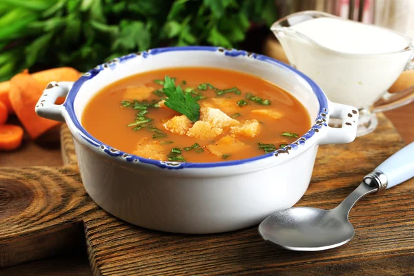 Composition avec soupe aux carottes, ingrédients et herbes sur fond de bois de couleur — Photo