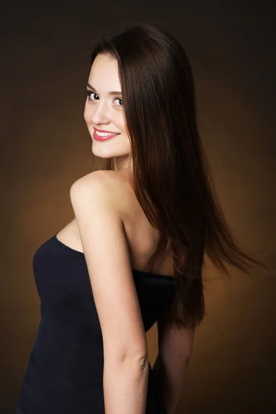 Beautiful young woman with long hair on dark brown background — Stock Photo, Image