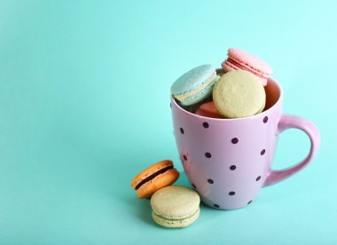 Renk arka plan üzerinde renkli mug içinde yumuşak renkli kurabiye çeşitleri