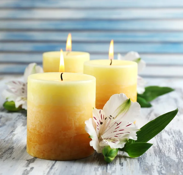 Schöne Kerzen mit Blumen auf Holzgrund — Stockfoto