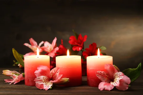 Mooie kaarsen met bloemen op houten tafel, op donkere achtergrond — Stockfoto