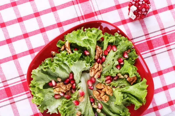 Fresh salad with greens, garnet and spices on plate on table close-up — Stock Photo, Image