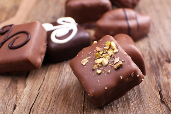 Varie caramelle dolci su sfondo strutturato in legno con cuore di cioccolato in primo piano — Foto Stock