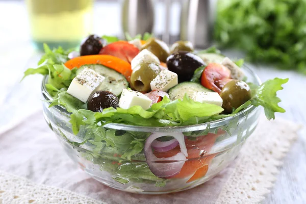 Salada grega em prato de vidro em guardanapo e cor de fundo de madeira — Fotografia de Stock