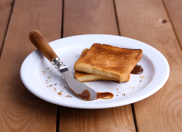 Toast brood met chocolade op plaat met mes op houten tafel achtergrond — Stockfoto