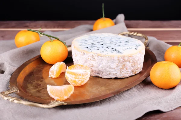 Blue cheese with oranges on metal tray on burlap cloth and wooden table background — Stock Photo, Image