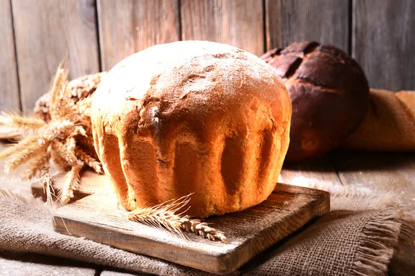 Pão saboroso na mesa no fundo de madeira — Fotografia de Stock