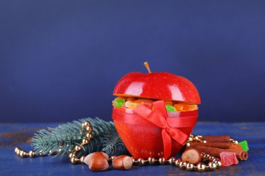 Kuruyemiş tarçın, çam ağacı ve renk ahşap masa ve koyu arka plan üzerinde fındık fışkın ile kırmızı elma dolması