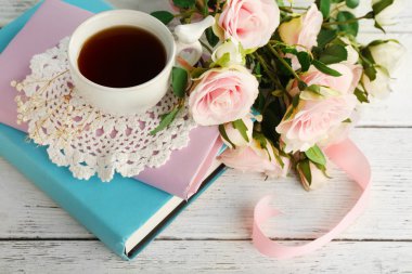 Kitaplar ve çiçeklerle ahşap arka plan üzerinde çay