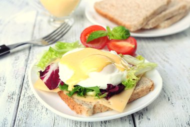 Yumurta Benedict ile tost ve ahşap masa üzerinde tabakta domates