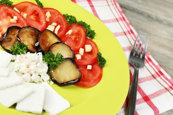 Auberginen-Salat mit Tomaten und Feta, auf Serviette, auf Holzgrund — Stockfoto