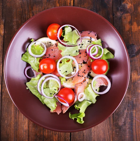 Fresh fish salad with vegetables on plate on wooden table close-up — Stock Photo, Image