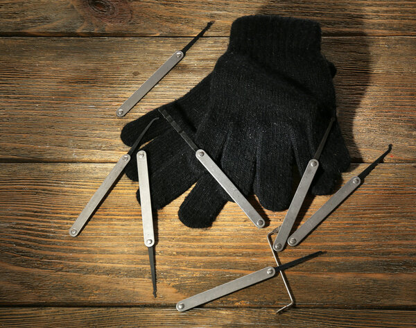 Lock picks with gloves on wooden table