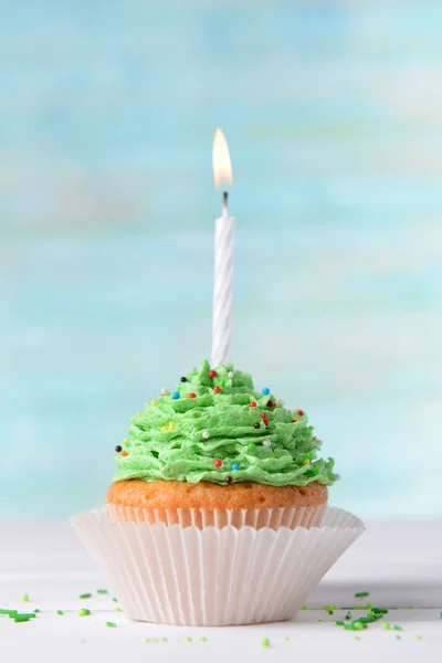 Delicioso cupcake de aniversário na mesa no fundo azul claro — Fotografia de Stock