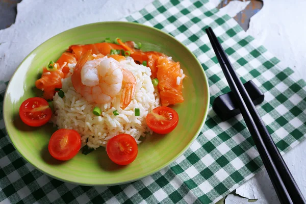 Варёный рис и креветки, лосось на тарелке, на деревянном фоне — стоковое фото