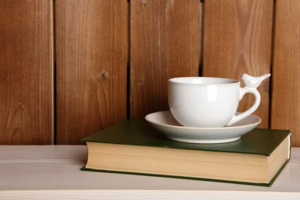 Copa de bebida caliente en el libro sobre la mesa y el fondo de madera —  Fotos de Stock