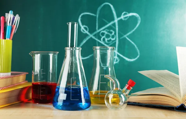 Bureau en classe de chimie avec éprouvettes sur fond de tableau noir vert — Photo