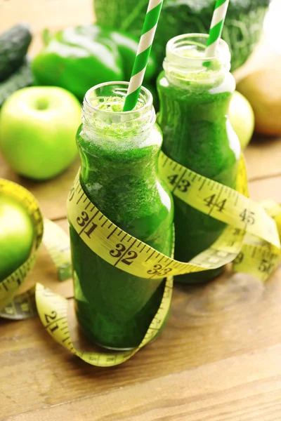 Zumo verde fresco y saludable en botellas de vidrio con frutas y verduras sobre fondo de mesa de madera — Foto de Stock