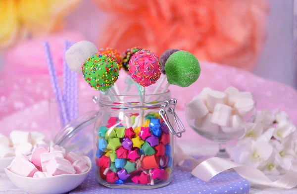 Söta cake pops i burken på bordet på ljus bakgrund — Stockfoto