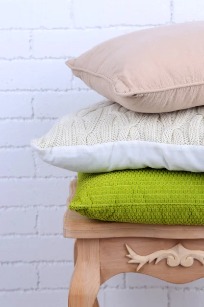 Almohadas sobre una pequeña mesa de madera y fondo de pared de ladrillo blanco — Foto de Stock