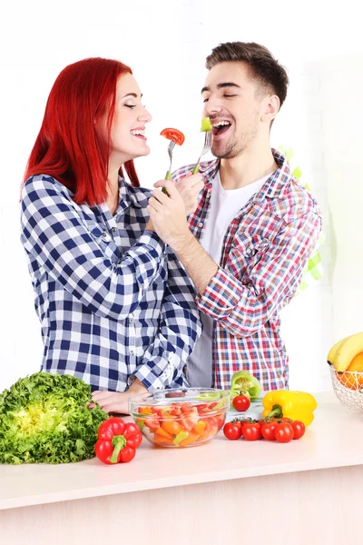 Pareja feliz preparando ensalada de verduras en la cocina —  Fotos de Stock