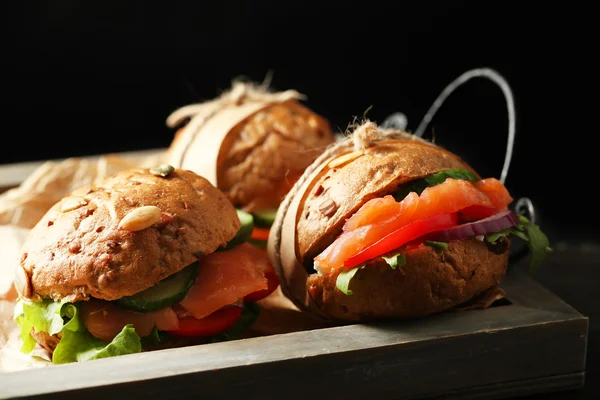 Sandwiches con salmón en bandeja, sobre fondo oscuro — Foto de Stock