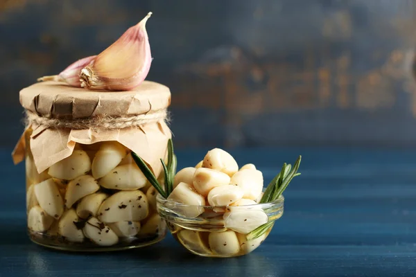 Canned garlic in glass jar on color wooden background — Stock Photo, Image