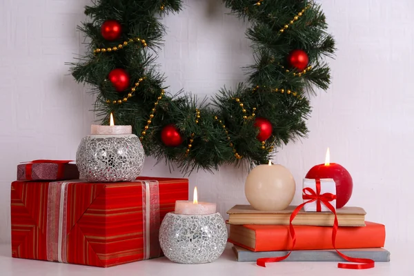 Vánoční dekorace, věnce, svíčky a současné boxy na polici na zdi bílé pozadí — Stock fotografie