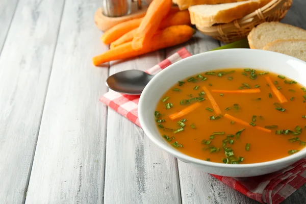 Karottensuppe, Sahne und Löffel, auf farbigem Holzgrund — Stockfoto