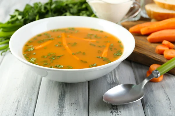 Composition avec soupe aux carottes, ingrédients et herbes sur fond de bois de couleur — Photo
