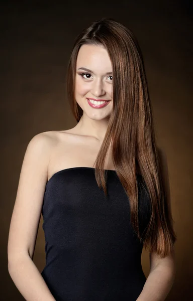 Beautiful young woman with long hair on dark brown background — Stock Photo, Image