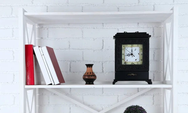 Étagères avec livres et objets décoratifs sur fond de mur de briques — Photo