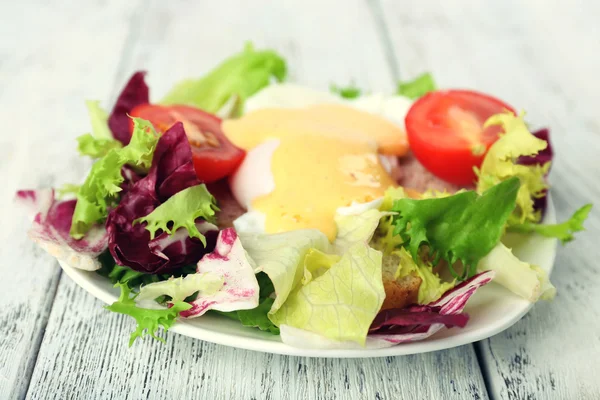 Toast with egg Benedict and tomato on plate on wooden table — Stock Photo, Image