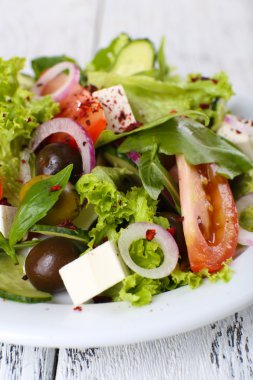 Plaka renk ahşap masa arka plan üzerinde Yunan salatası