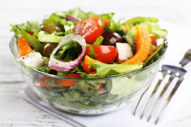 Cam tabak peçete ve renk ahşap arka plan üzerinde Yunan salatası