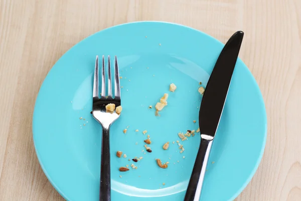 Plate with crumbs on wooden background — Stock Photo, Image