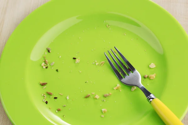 Plate with crumbs and used fork on wooden background — Stock Photo, Image