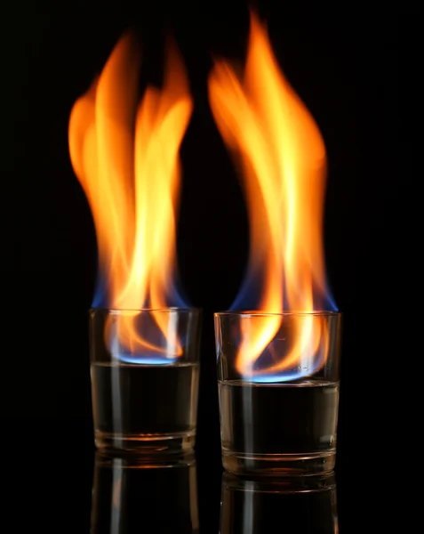 Glasögon med brinnande alkohol på svart bakgrund — Stockfoto