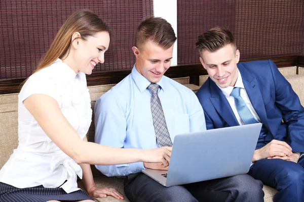 Young business people sitting on couch in office — Stock Photo, Image