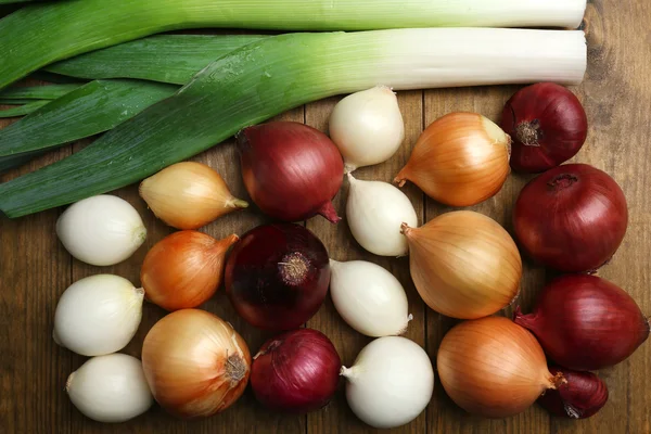 Different raw onion on wooden background — Stock Photo, Image