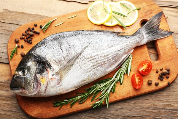 Свежая рыба и пищевые ингредиенты на столе — стоковое фото