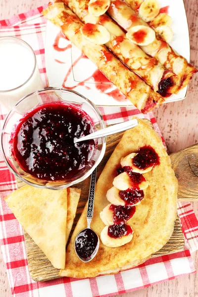 Heerlijke pannenkoeken met jam van de Bes en bananen op houten bord, op houten achtergrond — Stockfoto