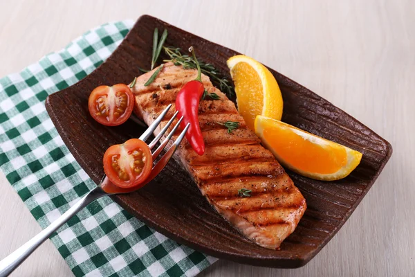 Grilled salmon and vegetables on plate on wooden background — Stock Photo, Image