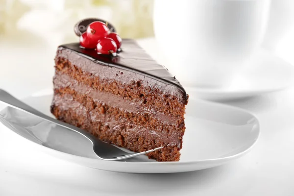 Delicious chocolate cake on plate on table on light background — Stock Photo, Image