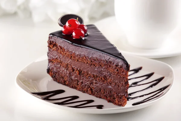 Νόστιμο κέικ σοκολάτας στο πιάτο στο τραπέζι στο φως φόντο — Φωτογραφία Αρχείου