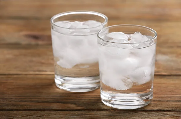 Gafas con cubitos de hielo sobre mesa de madera — Foto de Stock