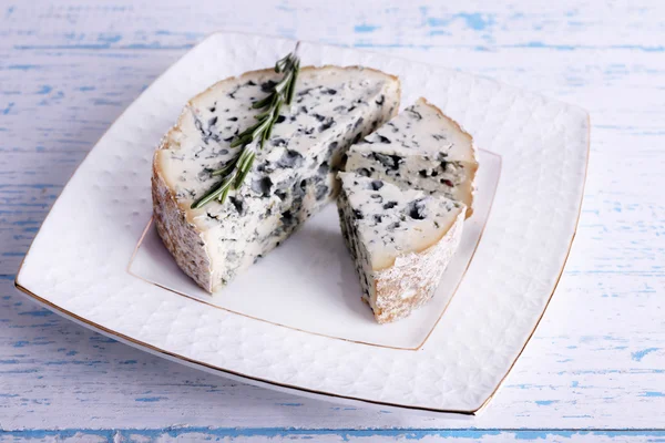 Blue cheese with sprigs of rosemary on plate and color wooden table background — Stock Photo, Image
